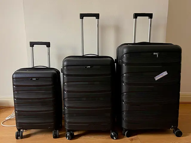 Charcoal hard-shell suitcase set standing upright on wooden a floor.